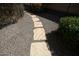 Stone walkway through a well-maintained gravel backyard with lush bushes at 27083 W Marco Polo Rd, Buckeye, AZ 85396