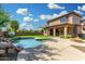 Resort-style backyard with a large pool, rock waterfall feature, covered patio and a built-in fire pit at 3099 E Claxton Ct, Gilbert, AZ 85297