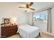 Bright bedroom with a wooden dresser, ceiling fan, and large window with natural light at 3306 W Lupine Ave, Phoenix, AZ 85029