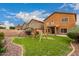 A well-maintained backyard features a grassy lawn and a play structure under a sunny, partly cloudy sky at 41227 W Granada Dr, Maricopa, AZ 85138