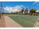 Well-maintained community basketball court with green surface, surrounded by mature trees under a bright sky at 41227 W Granada Dr, Maricopa, AZ 85138