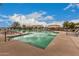 Large community swimming pool area with clear water, lounge chairs, and shade structures on a sunny day at 41227 W Granada Dr, Maricopa, AZ 85138