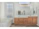 Well-lit bathroom featuring double sinks, wood cabinets, and bathtub at 4718 E Decatur St, Mesa, AZ 85205