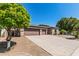 Single-story home featuring a three-car garage, desert landscaping, and mature trees in the front yard at 4718 E Decatur St, Mesa, AZ 85205