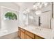 Bright bathroom features a double sink vanity, a soaking tub under an arched window, and a glass-enclosed shower at 4811 W Oakland St, Chandler, AZ 85226