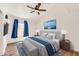 Comfortable bedroom featuring a ceiling fan, a large picture window with blue curtains, and an artistic wall decoration at 4811 W Oakland St, Chandler, AZ 85226