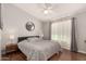 Cozy bedroom with neutral walls, wood floors, ceiling fan, and modern round mirror at 5215 W Del Rio St, Chandler, AZ 85226