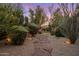 Beautiful backyard featuring a stone walkway lined with gravel and desert landscaping at dusk at 9417 E Charter Oak Dr, Scottsdale, AZ 85260