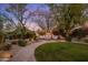 Backyard with fire pit lounge area, lush landscaping, and ambient lighting at 9417 E Charter Oak Dr, Scottsdale, AZ 85260