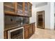 A custom wet bar features wood cabinets, granite counters, a wine fridge, and ample storage space at 9417 E Charter Oak Dr, Scottsdale, AZ 85260