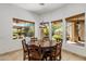 Bright dining area featuring travertine floors, wood-framed windows with backyard views, and a stylish hanging light fixture at 9417 E Charter Oak Dr, Scottsdale, AZ 85260