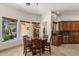 Bright dining area with travertine floors, wood-framed windows, a hanging light fixture, and custom cabinets at 9417 E Charter Oak Dr, Scottsdale, AZ 85260