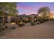 Desert home with lush landscaping, showcasing its curb appeal against a beautiful sunset backdrop at 9417 E Charter Oak Dr, Scottsdale, AZ 85260