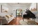 Elegant living room with hardwood floors, piano, comfortable couch, and an ornate doorway leading to the outdoor fountain at 9417 E Charter Oak Dr, Scottsdale, AZ 85260