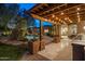 Covered patio with outdoor kitchen and BBQ area overlooking a beautifully landscaped backyard with pool and waterfall features at 9417 E Charter Oak Dr, Scottsdale, AZ 85260