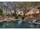 Backyard pool with rock waterfalls, lush landscaping, and ambient lighting for a serene and relaxing outdoor experience at 9417 E Charter Oak Dr, Scottsdale, AZ 85260
