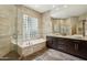 Bathroom with a luxurious soaking tub, glass block window, and dual sinks with granite countertops at 9540 N 114Th Way, Scottsdale, AZ 85259