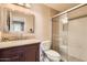 Well-lit bathroom featuring a tiled shower with glass doors, a granite vanity top, and a decorative mirror at 9708 E Via Linda -- # 1338, Scottsdale, AZ 85258