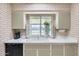 Bright kitchen featuring a window with a view, white countertops and appliances and brick walls at 9805 W Burns Dr, Sun City, AZ 85351