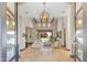 Spacious living room with travertine floors, wood beams, large windows, statement light fixture, and retractable glass doors at 37334 N Winding Wash Trl, Carefree, AZ 85377