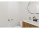 Modern half bath with a wood vanity, white sink, black faucet, and round mirror at 4422 E Dry Creek Rd, Phoenix, AZ 85044