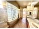 This renovated bathroom showcases a glass-block shower, tile flooring, and a double vanity with upgraded fixtures at 702 E Capricorn Way, Chandler, AZ 85249