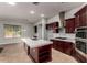 A spacious kitchen with cherry wood cabinets, an island, stainless steel appliances, and tile backsplash at 702 E Capricorn Way, Chandler, AZ 85249