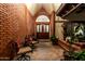 Inviting covered brick patio featuring stylish seating and potted plants, leading to a wooden front door at 908 N Creston --, Mesa, AZ 85213
