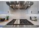 Close-up of a modern gas cooktop with stainless steel vent hood and white cabinets at 1250 E Smokehouse Trl, Phoenix, AZ 85085