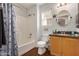 Bathroom featuring a shower-tub combo, a wooden vanity, and a round mirror over the sink at 1474 E Riviera Dr, Chandler, AZ 85249