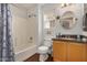 Bathroom featuring a shower-tub combo, a wooden vanity, and a round mirror over the sink at 1474 E Riviera Dr, Chandler, AZ 85249