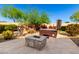 Backyard stone patio featuring a fire pit, hot tub, and lush desert landscaping at 17139 S 174Th Dr, Goodyear, AZ 85338