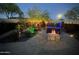 Backyard oasis with a hot tub, a fire pit, landscape lighting, and lush landscaping, perfect for relaxation at 17139 S 174Th Dr, Goodyear, AZ 85338