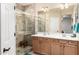 Bright bathroom featuring double sinks, wooden cabinets, and glass-enclosed shower with tiled walls at 17139 S 174Th Dr, Goodyear, AZ 85338