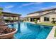 Backyard with a large pool, an outdoor kitchen and manicured landscaping on a sunny day at 17937 E Colt Ct, Queen Creek, AZ 85142