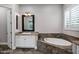 Bright bathroom with a soaking tub, shuttered window, and a vanity with marble countertops at 17937 E Colt Ct, Queen Creek, AZ 85142