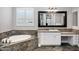 A luxurious bathroom featuring a soaking tub, elegant vanity, and large framed mirror at 17937 E Colt Ct, Queen Creek, AZ 85142