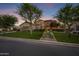 Home exterior with a green lawn and desert landscaping at dusk at 17937 E Colt Ct, Queen Creek, AZ 85142