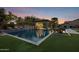 A luxurious pool with a built-in waterfall feature, an outdoor kitchen, and a spa at 17937 E Colt Ct, Queen Creek, AZ 85142