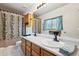 Bright bathroom featuring double sinks, oak cabinetry, neutral shower curtain, and a framed window at 263 S Del Rancho --, Mesa, AZ 85208