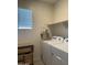 Bright laundry area with white appliances, wooden shelf, storage basket, and window for natural light at 3012 N 310Th Ln, Buckeye, AZ 85396