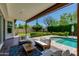 Inviting covered patio featuring plush seating, string lights, and a view of the backyard pool and greenery at 3229 E Campbell Ave, Phoenix, AZ 85018
