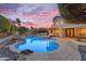 Inviting backyard pool with rock features, lounge seating, and manicured landscaping against a colorful sunset sky at 3623 S Agave Way, Chandler, AZ 85248