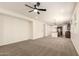 Open-concept living area with neutral carpet and a ceiling fan, seamlessly flowing into the kitchen at 40800 W Rio Grande Dr, Maricopa, AZ 85138