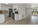 Open-concept kitchen adjacent to the living area features white cabinets, modern appliances, and wood flooring at 418 E Woodman Dr, Tempe, AZ 85283