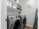 Functional laundry room equipped with modern washer and dryer units and storage shelving at 4337 E Vaughn Ave, Gilbert, AZ 85234