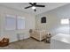This carpeted bedroom has a ceiling fan, baby crib, and window at 4633 E Desert Cactus St, Phoenix, AZ 85032