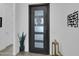 Modern front door with frosted glass and black metal frame, complemented by sleek planters and interior decor at 5951 N 190Th Dr, Litchfield Park, AZ 85340