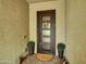 Inviting front entrance with a dark wood door with glass panels, potted plants, and a decorative welcome sign at 5951 N 190Th Dr, Litchfield Park, AZ 85340