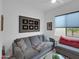 Cozy living room featuring a gray sofa with decorative pillows, art, and a window letting in natural light at 5951 N 190Th Dr, Litchfield Park, AZ 85340